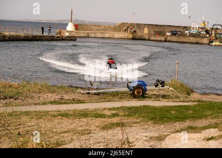 Two men riding a jet ski in the harbor of Port Seton near Edinburgh, UK Stock Photo