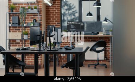 Computer screens on desk in empty data room and computers in background running programming code data algorithms. Neural network servers cloud computing in software it agency office. Stock Photo