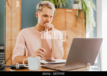 Happy business man sitting at cafeteria with laptop and smartphone. Businessman texting on smart phone while sitting in a cafe, working and checking e Stock Photo
