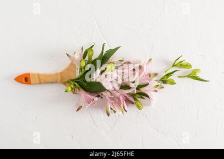 Beautiful spring flowers alstroemerieae in a composition with a brush. creative floral coloring. top view. white background Stock Photo