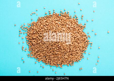 Buckwheat heap on blue background. Raw buckwheat on blue. Stock Photo