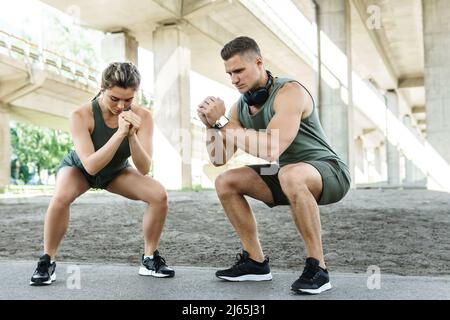 Athletic couple doing squats during street workout Stock Photo