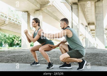 Athletic couple doing squats during street workout Stock Photo