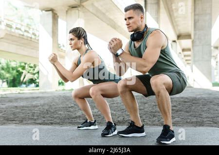 Athletic couple doing squats during street workout Stock Photo