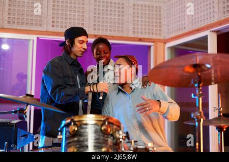Portrait of Latin-American woman rapping while having fun with music band in recording studio Stock Photo