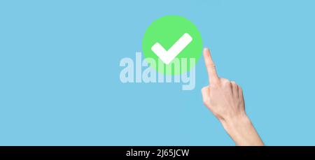 Hand holds green icon Check mark,Check Mark Sign, Tick Icon,right sign,circle green checkmark button,Done.On dark background.Banner.Copy space.Place f Stock Photo