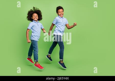 Full length body size view of trendy cheerful pre-teen friends friendship jumping strolling isolated over green color background Stock Photo