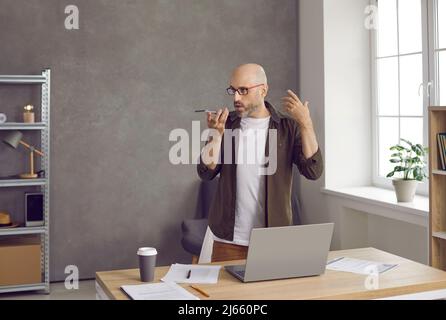 Businessman holding cellphone, recording voice message or talking on speakerphone Stock Photo