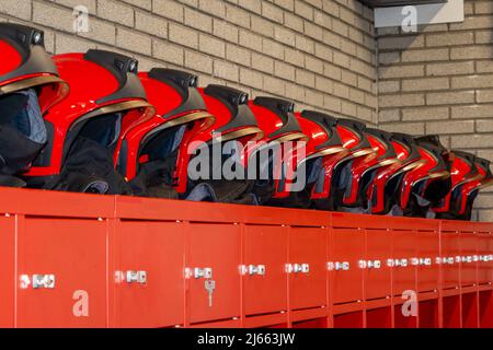 Red fire helmets placed in a row, on top of the fire brigade wardrobes. Ready to fight a fire or calamity Stock Photo