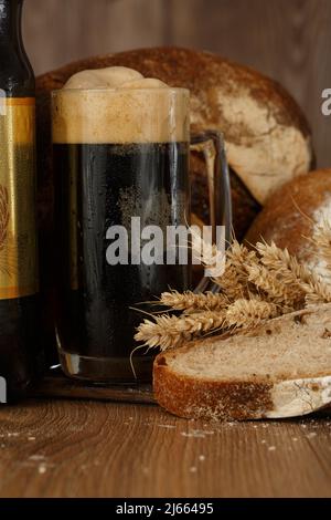 Traditional Russian drink kvass made from bread, rye malt, sugar and water. Kvass in the jug, rye bread and malt in a bowl with scoop on a dark wooden Stock Photo