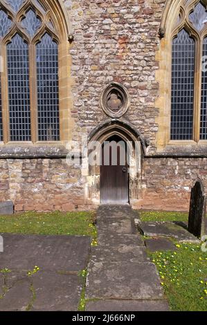 Small, carved side Door at Llandaff Cathedral, south side with gravestones and leaded windows in view. Stock Photo