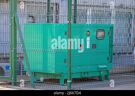 Emergency electric power generator outdoors  in metal cage Stock Photo