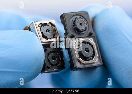 Smartphone camera modules in scientist hands. Different sensor sizes and technology. Stock Photo