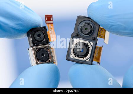 Smartphone single and dual camera modules in scientist hands. Different sensor sizes and technology used. Stock Photo