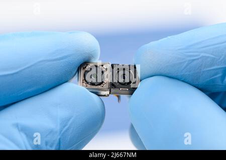Two small camera modules in scientist hands. Smartphone sensor technology research or repair concept. Stock Photo