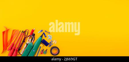 Arrangement of tools for repairing automotive electrical wiring on a yellow background. selective focus Stock Photo