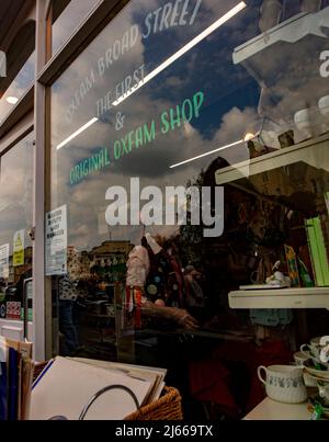 The first, original Oxfam shop, in Broad St, Oxford, UK; looking through the window at a woman in Morris dancing dress Stock Photo