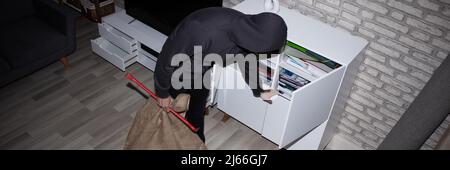 Elevated View Of Thief With Crowbar And Sack Stealing File From Shelf Stock Photo