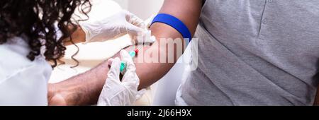 Close-up Of Doctor Taking Blood Sample From Patient's Arm Stock Photo