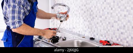 Mid Section Of Male Plumber Assembling The Kitchen Sink Faucet Stock Photo