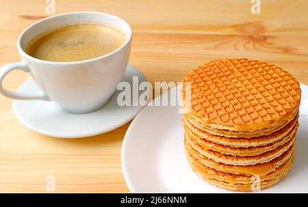 Stack of Delectable Dutch Stroopwafels on White Plate with Blurry Hot Coffee in the Backdrop Stock Photo