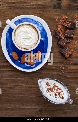 Blue cup of cappuccino almonds chocolate and milk in a glass milk jug Stock Photo