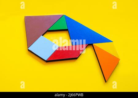 Colorful number 9 made with tangram toy, colored tangram number seven isolated on yellow background, side view of seventh numeric, kids game idea Stock Photo