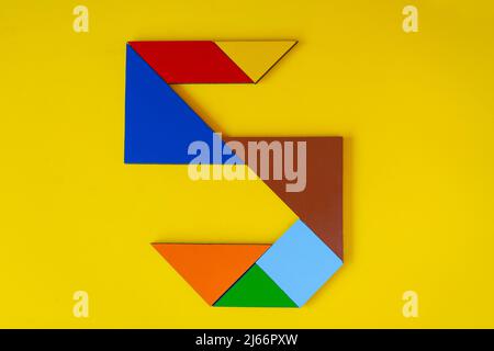 Colorful number 5 made with tangram toy, colored tangram number seven isolated on yellow background, side view of seventh numeric, kids game idea Stock Photo