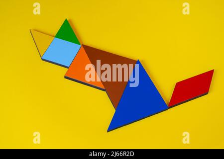 Tangram cat isolated on yellow background, sitting view of tangram animal cat, lay down, colorful tangram puzzle toy concept Stock Photo