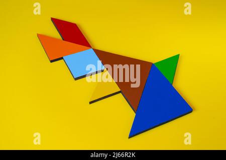 Tangram rabbit isolated on yellow background, sitting view of tangram animal rabbit, lay down, colorful tangram puzzle toy concept Stock Photo