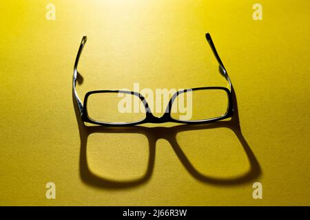 a pair of eyeglasses on a yellow surface Stock Photo