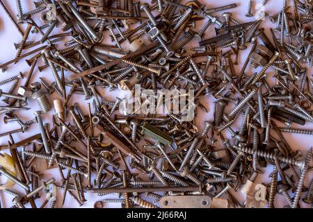 Pile of rusty nails and small hardware nuts, pile of oxidized nails and rivets scattered on the white background,top view Stock Photo