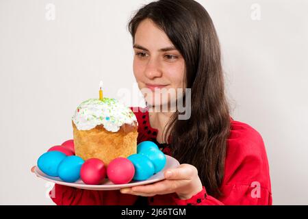 A woman holds an Easter cake and painted eggs on a white background, copy space for text. Stock Photo