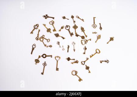 A pile of vintage golden skeleton keys isolated on white background. Golden skeleton keys in different shapes. Keys for locks and treasure boxes. Stock Photo