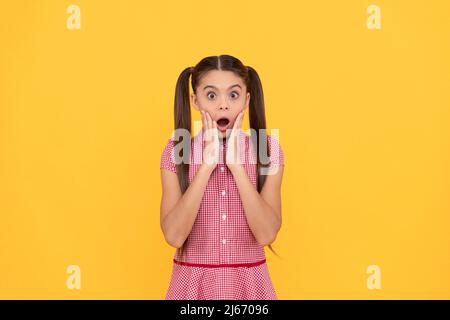 Kind of shocked. Kid got shocked. Surprised girl yellow background. Shock and surprise Stock Photo