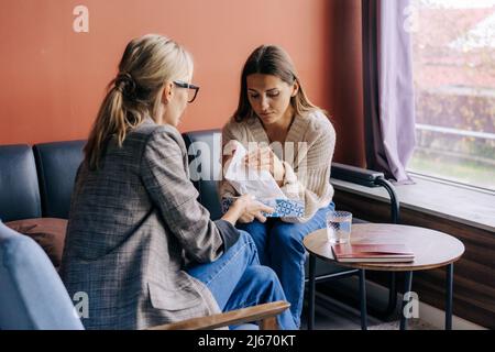 A sad crying woman on a visit to a psychotherapist talks about her problems and traumas. Stock Photo