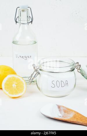 Baking soda in jar, vinegar, cut lemon, wooden spoon on a white background. The concept of removing stains on clothes. High quality photo Stock Photo