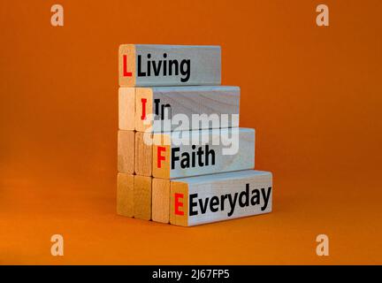 LIFE living in faith everyday symbol. Concept words LIFE living in faith everyday on wooden blocks on beautiful orange table orange background. Busine Stock Photo