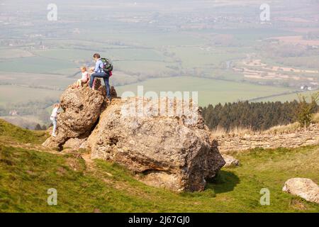 Families and children climbing on the the elephant stone on the summit of Bredon Hill in the Vale of Evesham Worcestershire England Stock Photo
