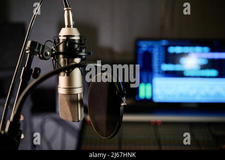 Horizontal no people selective focus shot of microphone with disc pop filter and mixing console in modern recording studio Stock Photo