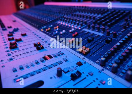 Horizontal no people shot of modern mixing console surface in recording studio in neon light Stock Photo