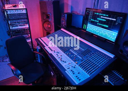 Horizontal no people shot of workspace in recording studio interior with mixing console, armchair, loudspeakers and other equipment Stock Photo