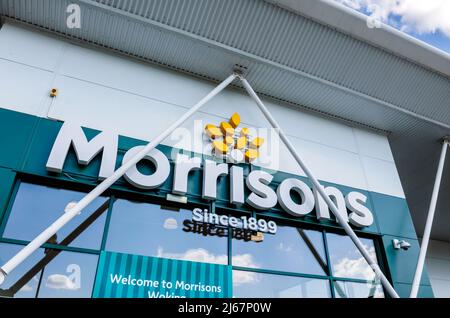 Morrisons name and logo above the entrance to its supermarket in Woking, Surrey, south-east England, viewed from below looking up Stock Photo