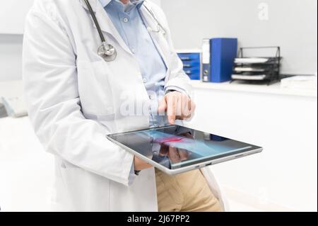 Unrecognizable Doctor is checking x-ray image at computer tablet, close up. Doctor at work in a hospital. Medicine and healthcare concept. High quality photography. Stock Photo