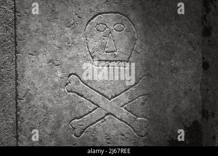 Skull and crossbones on the ancient tombstone. Sign of death Stock Photo