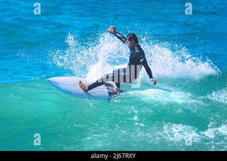 Surfer riding the wave on shortboard. Man catching waves in ocean. Water sports activity Stock Photo