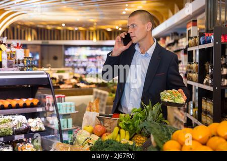 Young focused man using phone during shopping Stock Photo