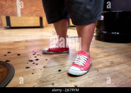 Barber's feet surrounded by hair on the floor Stock Photo