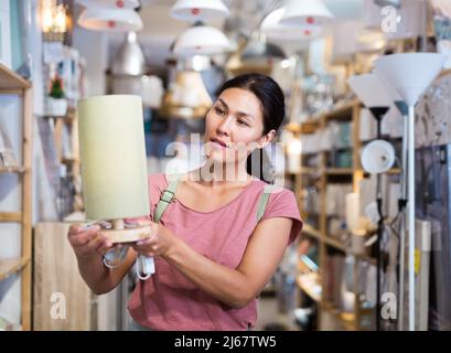 Asian woman choosing table lamp at store Stock Photo