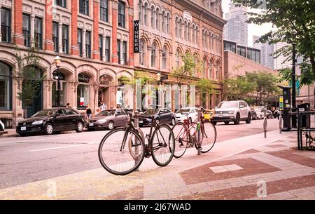 Toronto, Canada - 08 03 2018: two vintage bicycles parked on Front Street in front of old historic buildings. Cycling became popular healthier alterna